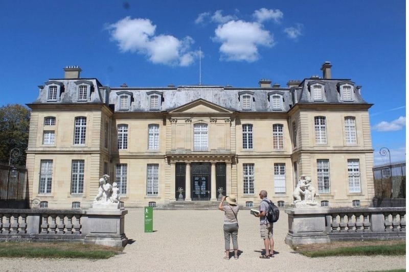 Front facade of Château de Champs-sur-Marne with classical statues and gravel path