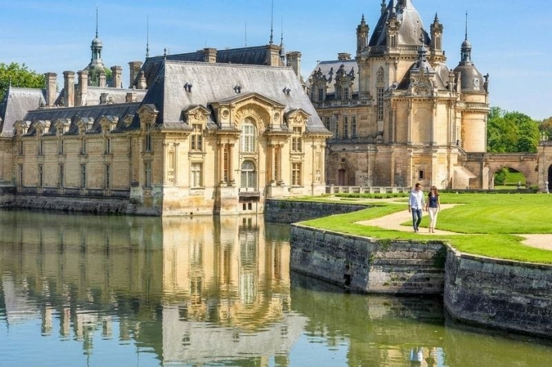 Château de Chantilly reflected in the surrounding moat on a sunny day