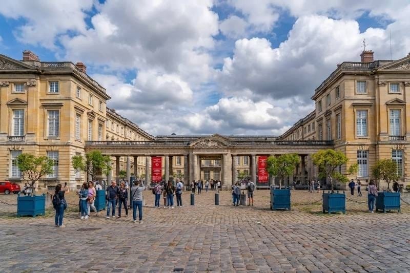 Courtyard of the Château de Compiègne with visitors on cobblestones