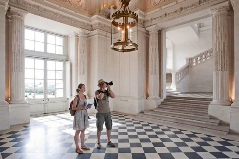 Grand interior hall of Château de Maisons with marble floors and staircase