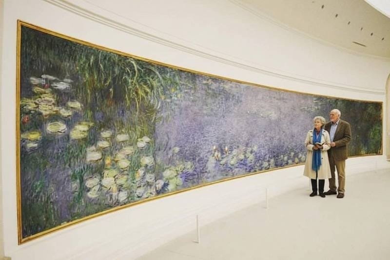 Visitors viewing Monet's monumental Water Lilies panels in the oval room at the Orangerie