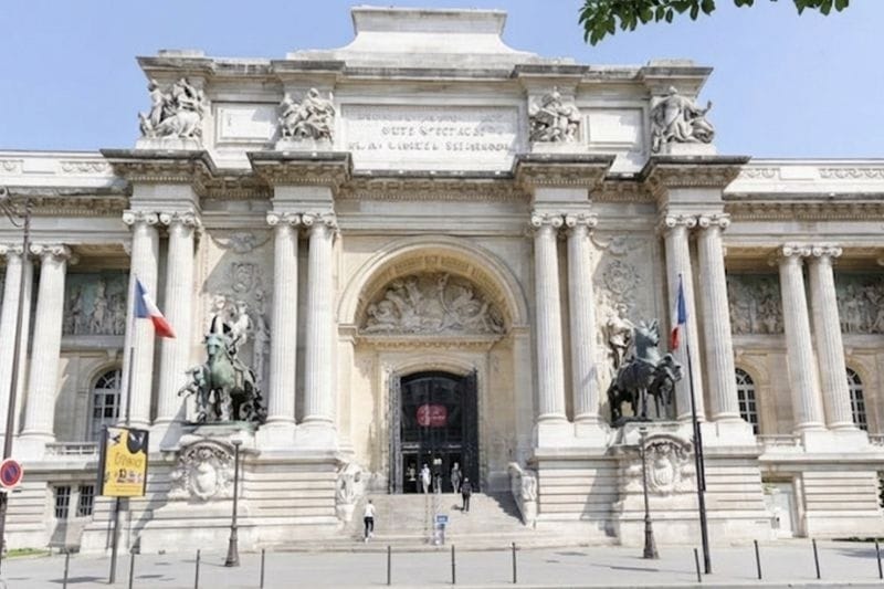 Neoclassical entrance of the Palais de la Découverte in Paris with French flags, bronze equestrian statues, and ornate stone columns